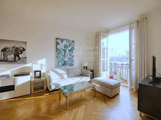 Living room with white sofa and parquet floor in this luxury apartment for sale in Paris 16ème ($2,017,996 - 136 m²)