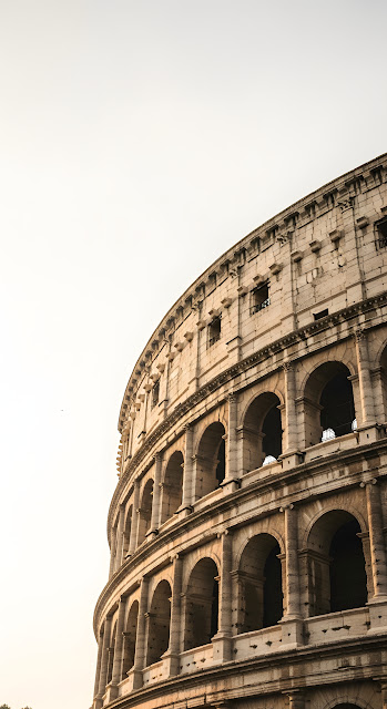Low-Angle Vertical View of Roman Colosseum Arches Against a Bright Sky - Free mobile Wallpaper
