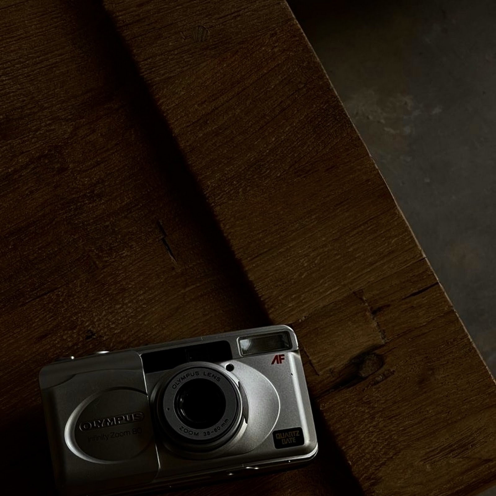 Download Silver Olympus Camera on Wood iPhone