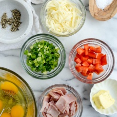 Chuẩn bị nguyên liệu. Trứng gà đánh tan, sau đó cho muối tiêu vào đánh đều, để riêng. Trong 1 cái chảo, bạn cho bơ vào đun chảy, sau đó cho ớt chuông, hành lá băm, thịt nguội vào xào chín sơ.