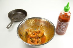 Cho tương ớt sriracha và bơ vào thau. Nhanh tay cho tôm vừa chiên và ít dầu ăn tiết ra từ tôm chiên vào thau, xóc đều cho đến khi bơ tan và hỗn hợp áo đều lên tôm là được.