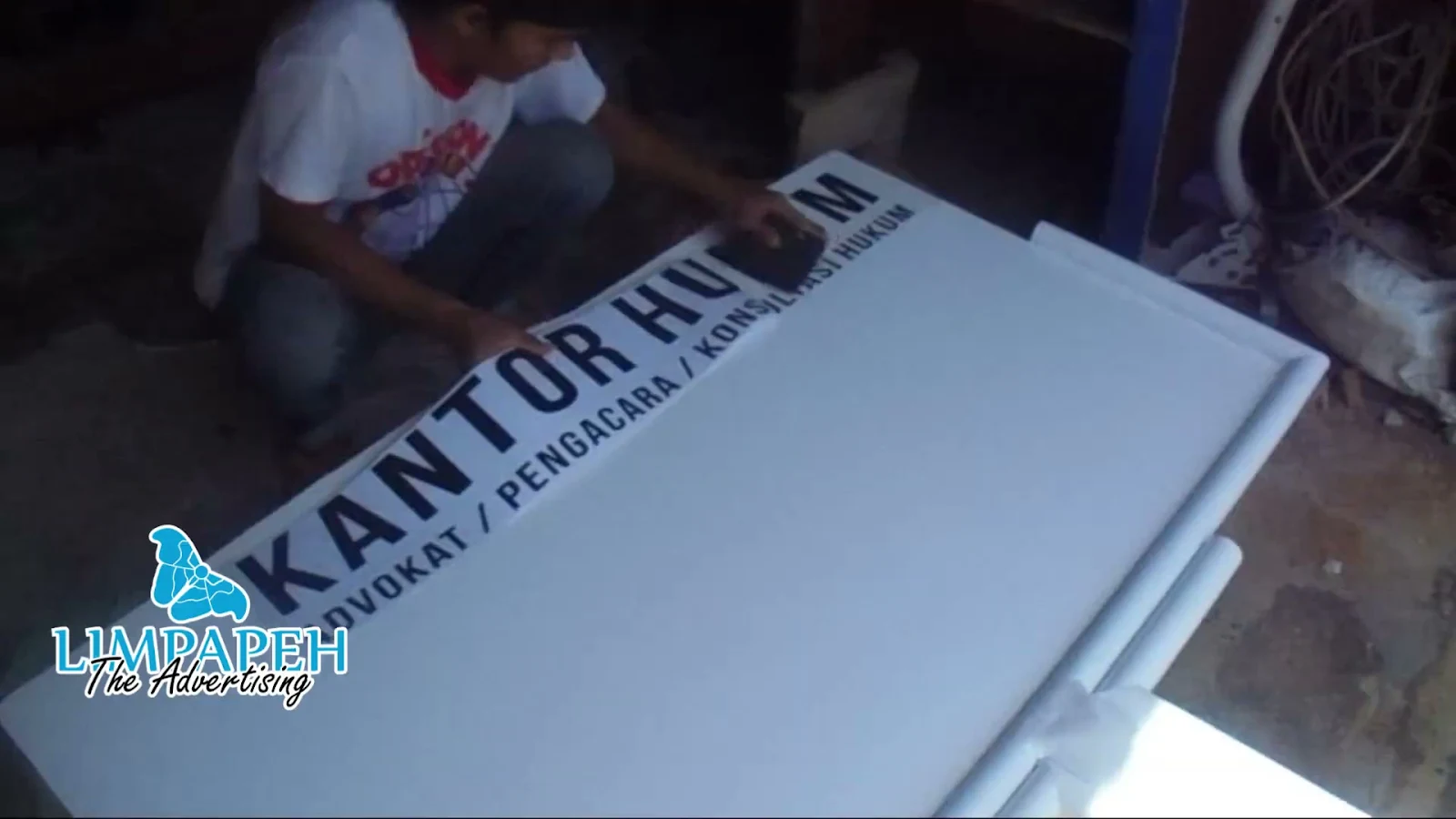 Proses pemasangan cutting sticker Oracal 651 pada papan nama kantor 200x100 cm oleh Limpapeh