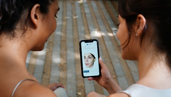 Photo prise de dos de deux patients regardant une simulation 3D sur un smartphone.