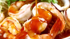 Cho lần lượt mì gói, tôm, mực, nghêu và giá, rau thơm vào tô. Rưới nước sốt chua cay vào. Thêm hành phi và dùng đũa trộn đều để các nguyên liệu thấm sốt.
