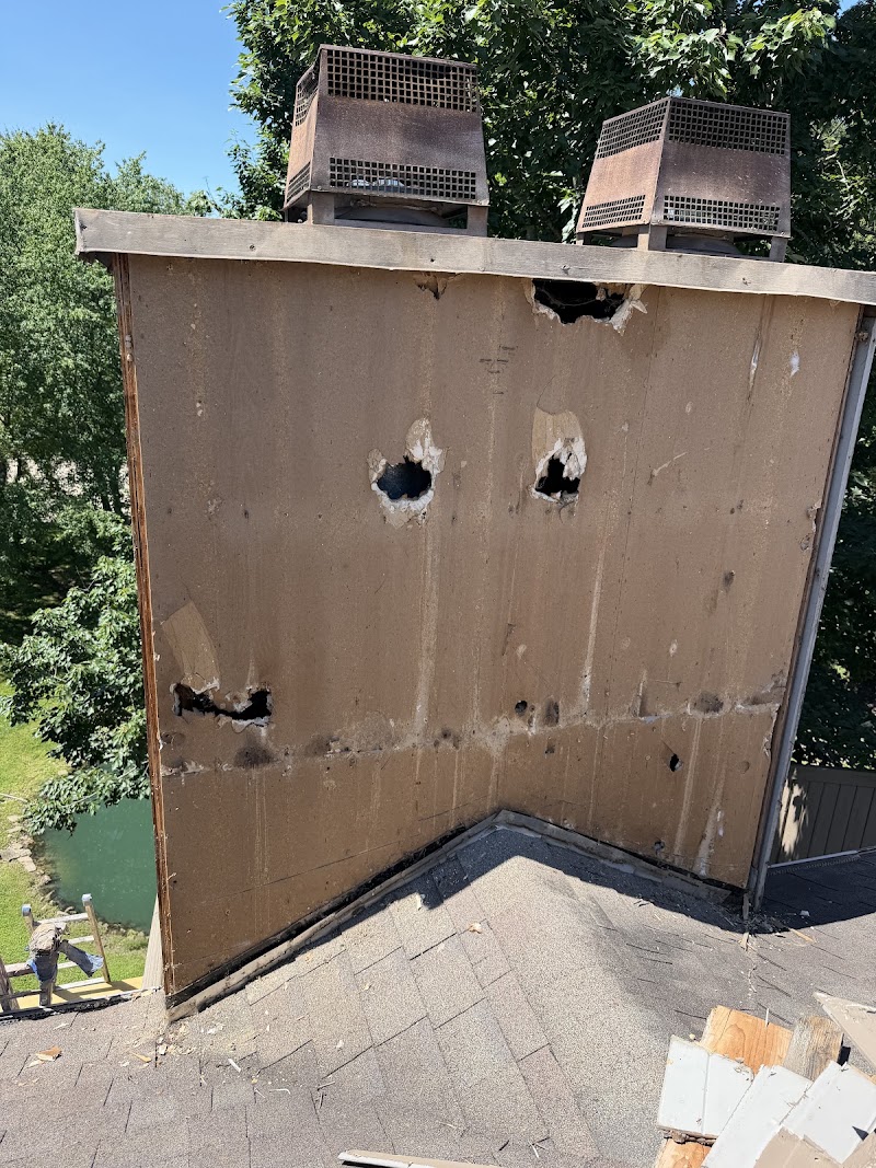Deteriorated plywood sheathing on the chimney at The Lookout after siding removal, with visible holes and failed surface