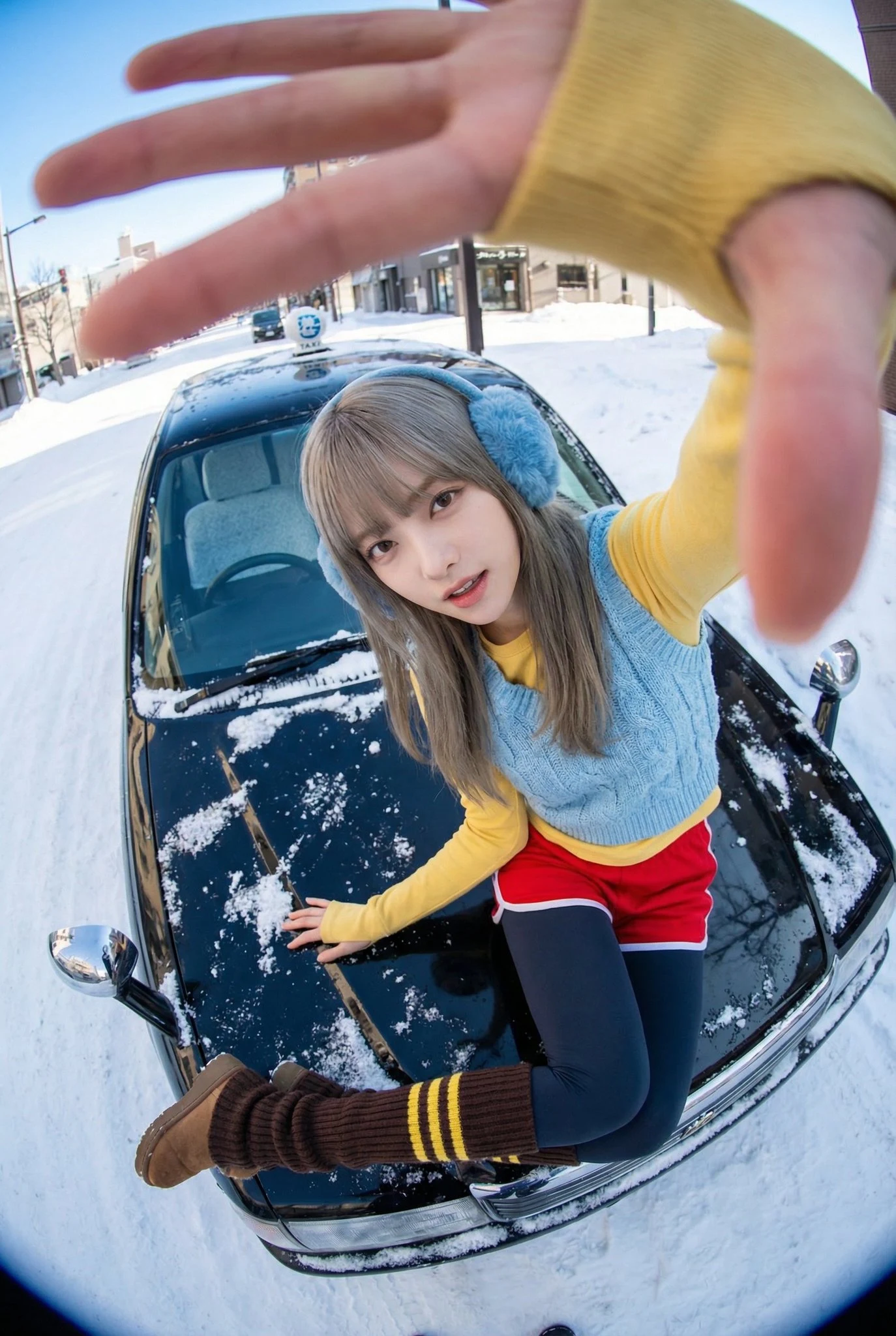 Mujer joven sentada sobre el capó de un taxi negro cubierto de nieve irregular, con ropa moderna, pose dinámica y distorsión de la perspectiva, llena de energía y con un estilo de moda Y2K.