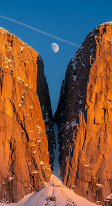 Close-up of Towering Golden Rock Cliffs with Moon and Contrail in Blue Sky