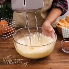 Dùng máy đánh trứng đánh bông lòng đỏ lên. Sau khi đánh được 5 phút thì cho từng đợt 50gr đường xay vào, đánh tiếp cho đến khi kem bông mịn.