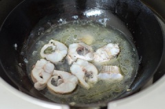 Đun nóng 2 muỗng canh dầu ăn rồi cho cá vào chiên sơ trong khoảng 10 phút thì cho 1/2 chén nước, gừng lát, đầu hành lá vào.