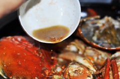 Khi cua chuyển màu đỏ thì cho hỗn hợp nước cốt me vào. Đảo đều để lửa nhỏ cho cua được thấm đều gia vị.