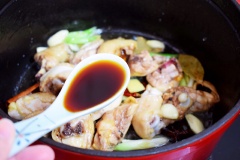 Nêm gia vị vào nồi gà kho gồm: 1 muỗng canh rượu nấu ăn, 1 muỗng canh nước tương, 1/2 muỗng canh hắc xì dầu, đảo đều cho thịt gà ngấm gia vị.