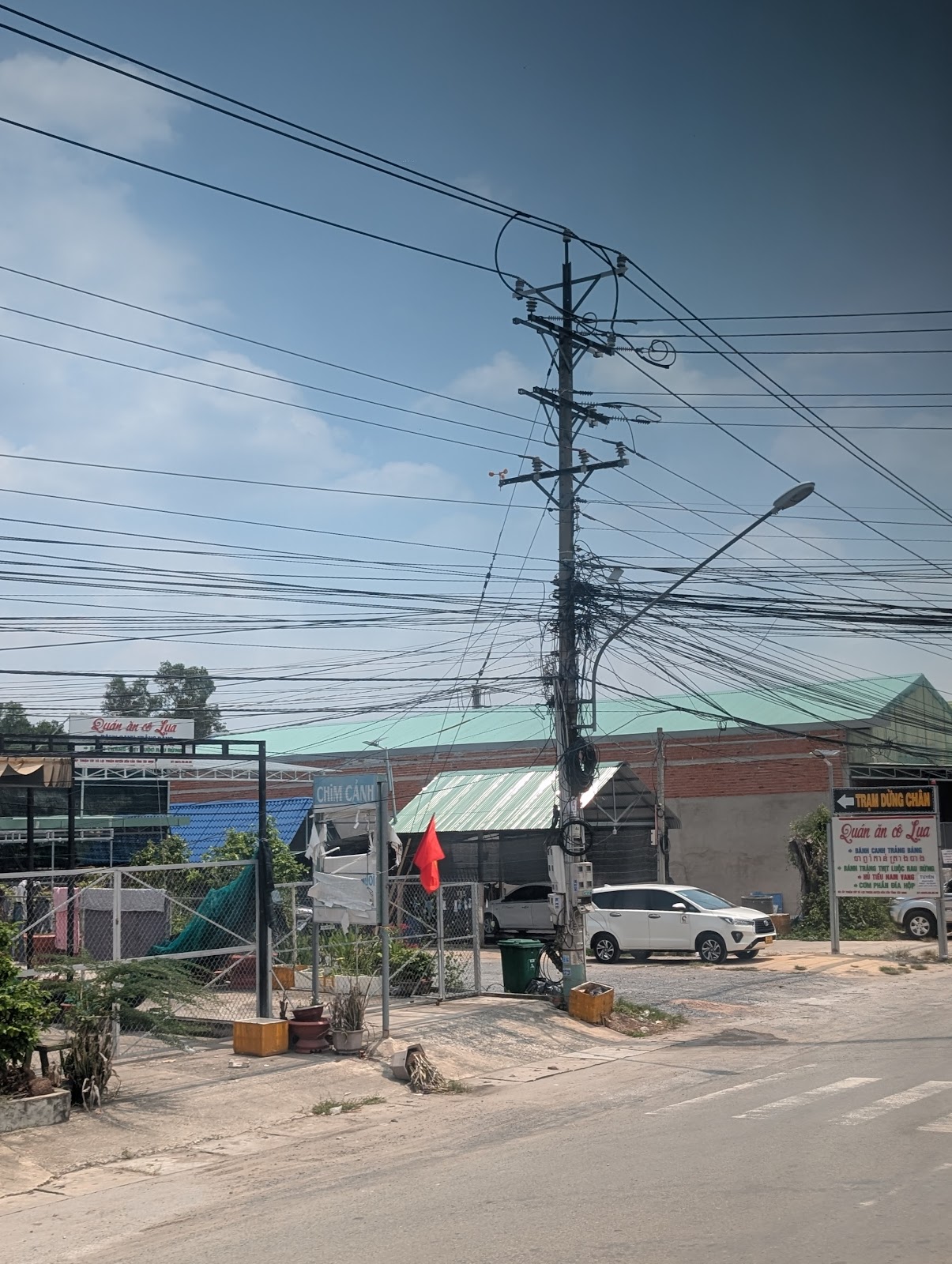 A tangle of overhead power and phone lines converging on a
                 single telephone pole.
