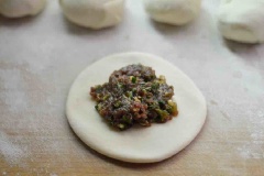 Bột sau khi nghỉ, chia thành những viên đều nhau. Cán mỏng dẹp rồi múc chút nhân thịt bò cho vào bọc kín lại. Sau đó lại cán nhẹ cho hơi dẹp.