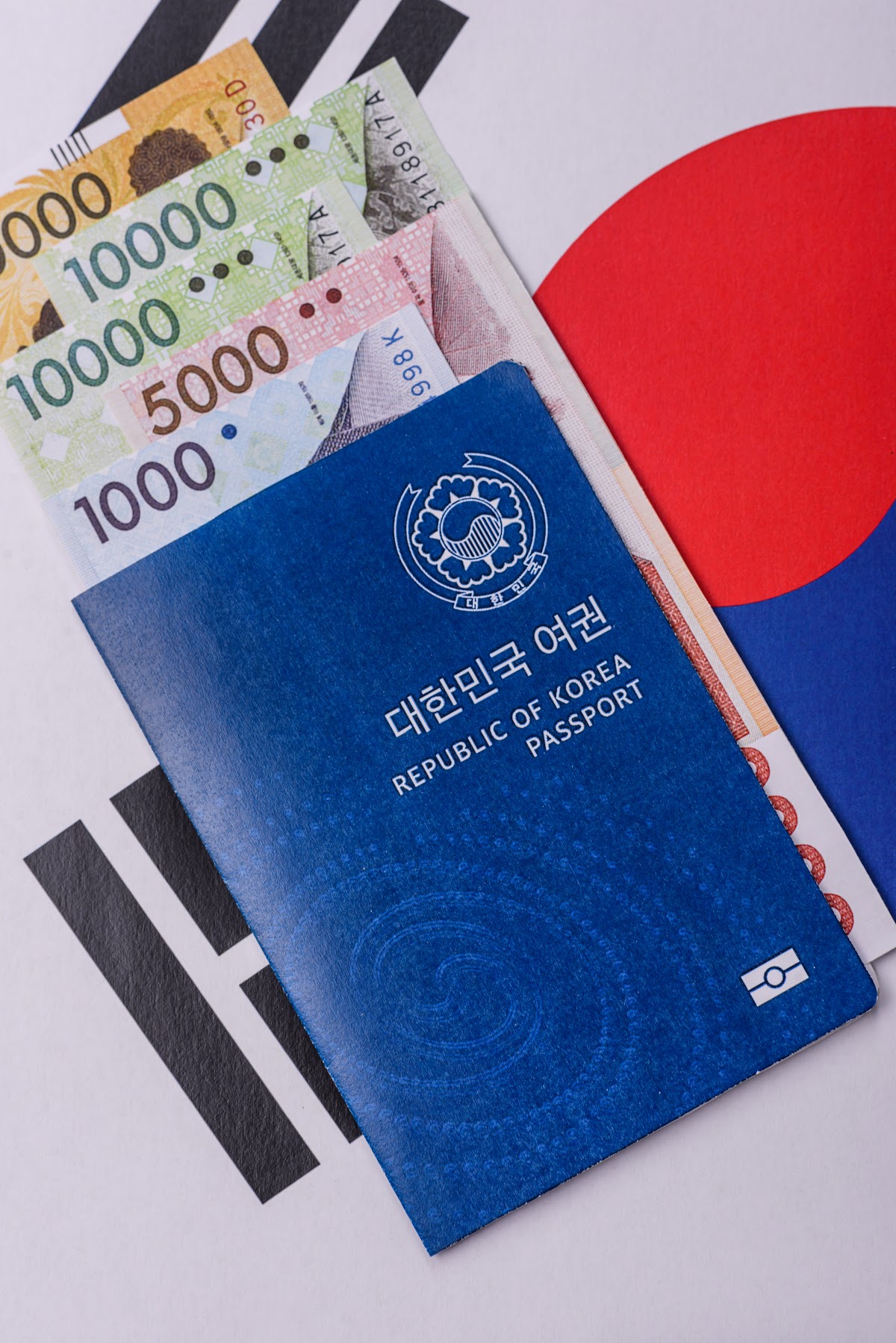 중국 비자 대행 안내 이미지, 태극기 배경 위에 대한민국 여권과 원화 지폐가 겹쳐 놓인 출국 준비 모습