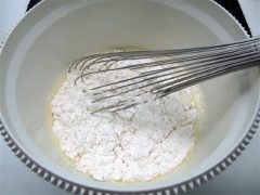 Trộn đều 200g bột mì, 1 muỗng canh bột nổi với 1/4 muỗng cà phê muối rồi rây vào hỗn hợp trứng, trộn đều. Sau đó, lọc hỗn hợp qua rây cho mịn.