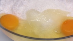 Cho vào tô 400g dừa nạo, 150g đường và 2 trứng gà rồi trộn đều lên thành hỗn hợp đồng nhất.