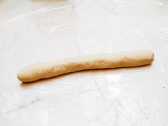 Cho bột mì và 50g đường vào tô, rưới từ từ nước vào và nhào thành khối rồi vê thành cuộn dài khoảng 20 cm. Sau đó, cắt làm 10 phần đều nhau.