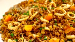 Dàn phần cơm rang qua 1/2 chảo, phần chảo còn lại thêm vào 1 muỗng canh dầu ăn, cho mực tươi vào chảo, thêm 20gr ớt sa tế khô, 15ml nước tương, 30gr dầu hào vào rồi xào cho đến khi mực săn lại và thấm gia vị. Tiếp theo trộn đều phần cơm rang và mực xào lại với nhau, đảo xóc đều tay cho đến khi cơm khô ráo, hạt cơm giòn tơi là được. Cuối cùng thêm vào phần trứng muối cắt nhỏ cùng 30gr hành lá cắt nhỏ, đảo lên lần nữa rồi tắt bếp.