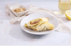 Bày trí bánh trứng cuộn thịt xông khói ra đĩa, có thể cắt làm đôi cho đẹp mắt nhé! Bạn có thể dùng ngay hoặc rưới lên ít sốt mayonnaise tùy thích.