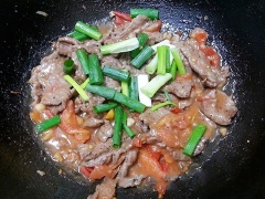 Vẫn cái chảo ấy, cho thêm 1 muỗng canh dầu ăn, nóng dầu, cho cà chua vào xào. Sau đó cho 1 muỗng canh nước mắm, 2 muỗng canh đường, 1 muỗng cà phê hạt nêm xào cho cà chua chín mềm. Thêm 2 muỗng canh nước đun sôi thì trút thịt bò vào đảo đều, nêm lại gia vị sao cho có độ chua ngọt vừa miệng rồi cho hành lá thái khúc vào đảo đều và tắt bếp.