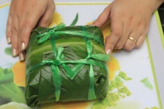 Gói bánh chưng cốm kín lại theo hình vuông. Dùng tay ấn và tạo khối cho ngay ngắn và buộc dây cho chặt.