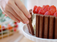 Bày bánh nướng ra đĩa, phết kem whipping đều các mạt bánh và xếp các thanh kitkat xung quanh bánh, thêm dâu tây lên mặt bánh là hoàn tất.