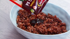 Cho 100gr cơm gạo lứt nấu chín để nguội vào tô, trộn đều cùng 2 muỗng canh xốt gia vị hoàn chỉnh Barona - Thịt nướng sả.