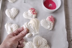 Bánh đã nướng xong bạn cho ra ngoài để nguội. Đun chảy chocolate trắng, nhúng một phần rìa của bánh vào chocolate trắng rồi nhanh tay rải kẹo cốm đủ màu lên, để nơi thoáng mát cho đông lại là hoàn thành món bánh cookie meringue trái tim này rồi.