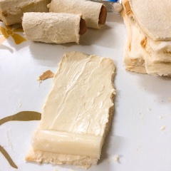 Sau khi xong bước chuẩn bị, đầu tiên quết phô mai lên một miếng sandwich đã cắt đôi sau đó cho 1 thanh xúc xích chiên vào cuộn lại. Tiếp theo tiếp tục quết trứng gà lên một miếng sandwich khác, đặt sandwich xúc xích đã thực hiện lên trên và cuộn lại.