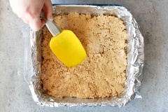 Chuẩn bị 1 khuôn khoảng 20x20cm, lót giấy nến hoặc giấy bạc vào khuôn. Đun chảy kẹo xốp (marshmallow), cho marshmallow và bơ đậu phộng trộn đều với nhau bằng máy đánh trứng, cho cốm ngũ cốc vào tiếp tục trộn. Múc hỗn hợp ra khuôn và nén thật phẳng.