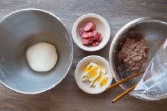 Chuẩn bị phần nhân bánh bao bằng cách cho thịt heo bằm trộn đều cùng lòng đỏ trứng gà, hẹ băm, dầu hào, nước mắm, 1 muỗng cà phê đường trắng và bột bắp. Trộn thật đều với nhau và quết vài lần để nhân bánh được dẻo dai. Trứng gà luộc chín rồi bóc vỏ, thái múi cau, để riêng trong bát. Lạp xưởng chiên chín rồi thái nhỏ, cũng để riêng như hình.