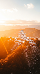 Misty Aerial of White Japanese Castle on Hill During Golden Hour in Winter