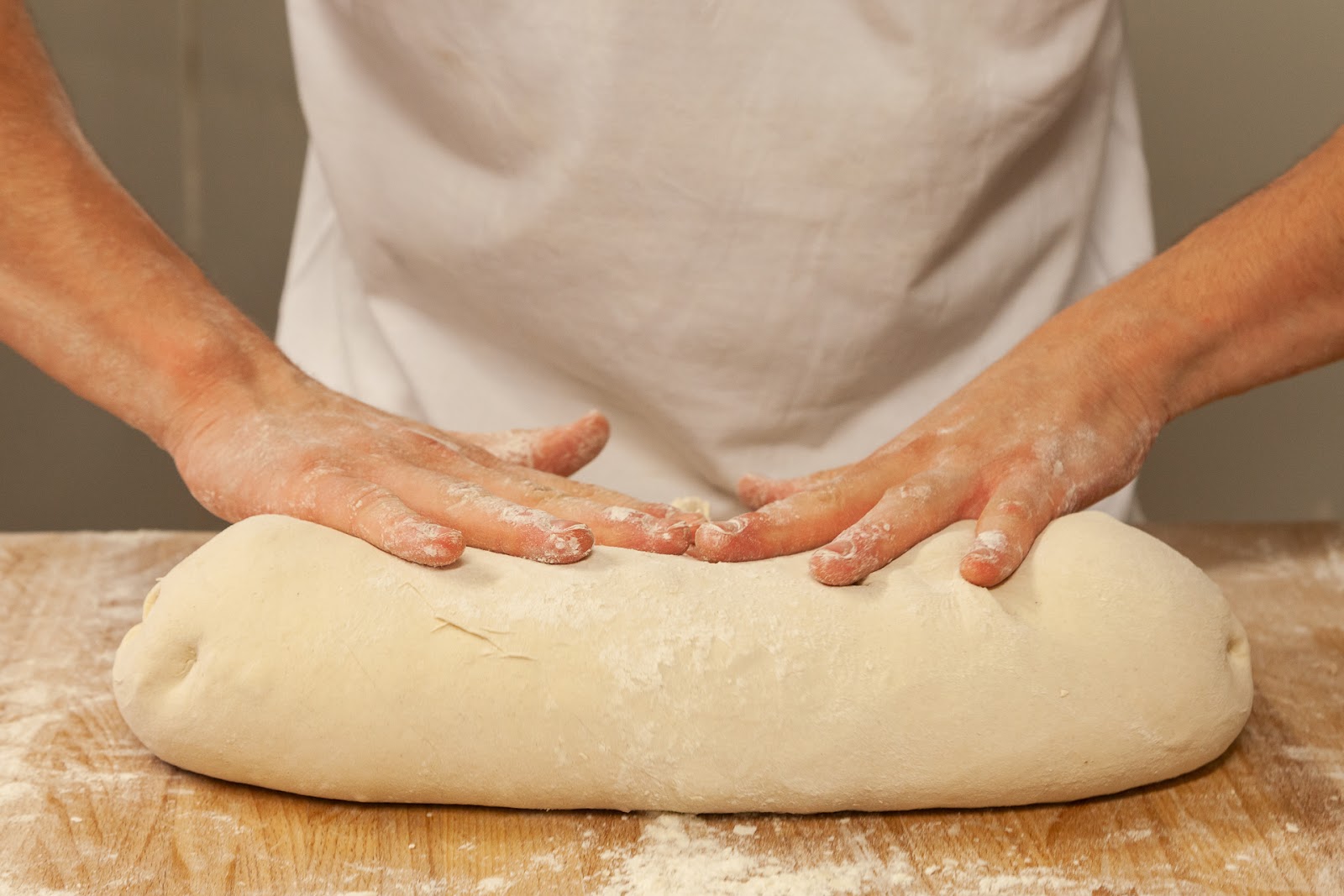 Mains d’artisan façonnant une pâte sur un plan de travail fariné