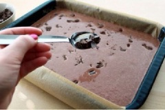Từ từ rót hỗn hợp vào khuôn. Chocolate nghiền nhỏ trong chén. Sau đó, rắc chocolate lên trên.