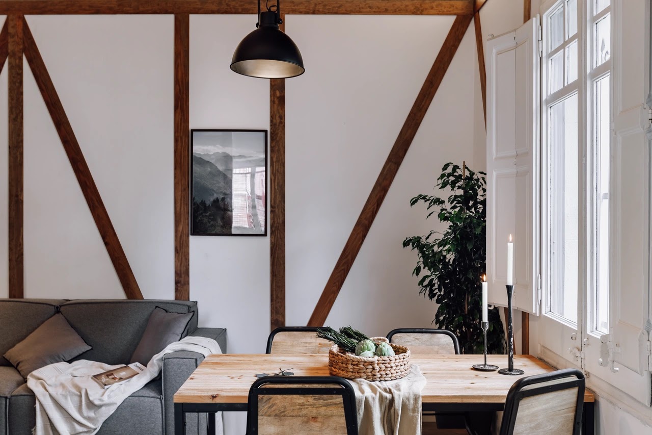 Primer plano de la mesa del comedor junto a la ventana de la sala principal y la pared rematada con madera al fondo.