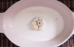Trộn muối biển cùng với hạt thì là, ngũ vị hương sau đó chà đều lên lớp bì. Cho sữa tươi vào khay cùng một củ tỏi đã cắt cho bằng phần đầu tỏi.