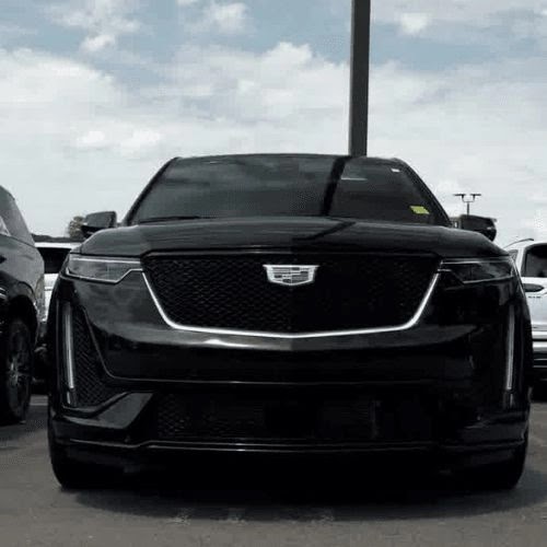 Front view of a black Cadillac XT6 parked outdoors under a cloudy sky