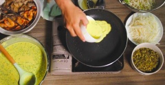 Làm nóng chảo và dùng cọ hoặc đập dập thân chuối quét một lớp dầu mỏng, cho ½ chén bột (mình dùng chén ăn cơm thông thường) đổ bột từ tâm chảo ra ngoài. Chỗ này nếu bạn nào dùng chảo lòng sâu, không phải chảo đế bằng thì đỗ từ thành chảo vào trong nha. Dùng tay đảo và xoay tròn chảo để bánh được tròn và đẹp. Cho topping vào, đậy nắp khoảng 2-3 phút. Chỗ này lưu ý là lửa lớn hay nhỏ mà thời gian đậy nắp sẽ dài hay ngắn nha.