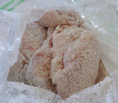 Cho bột năng vào 1 cái bao nylon, tiếp tục cho cánh gà vào xóc đều cho bột bám quanh cánh gà.