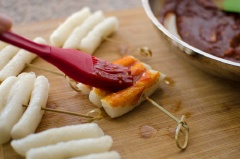 Đặt chảo lên bếp, cho 2 muỗng canh dầu ăn vào, đun nóng thì cho bánh gạo vào chiên hơi vàng thì vớt bánh gạo ra, đặt lên giấy thấm dầu cho giảm bớt dầu thừa. Cho tất cả các nguyên liệu còn lại vào chảo, đặt lên bếp đun sôi là được. Dùng chổi phết đều lớp sốt này lên trên mặt bánh gạo.