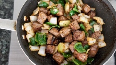 Đun nóng 1 muỗng canh dầu ăn trong chảo, phi thơm tỏi băm, cho phần thịt bò vào chiên đến khi cả hai mặt vàng nâu. Lưu ý chỉ lấy phần thịt bò, còn phần nước sốt từ bò vẫn giữ nguyên trong bát. Lần lượt thêm hành tây, ớt chuông vào, đảo đều tay. Lần lượt thêm hành tây, ớt chuông vào, đảo đều tay. Cuối cùng, khi hành tây và ớt chuông bắt đầu chín đều thì trút phần nước sốt ướp vào, xào cho thịt bò được phủ đều nước sốt thì tắt bếp.