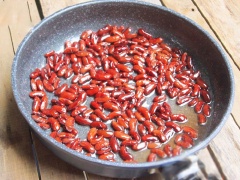 Cho khoảng 1 bát to nước vào chảo, thêm đường (cứ 1kg đậu thì dùng khoảng 500g đường), đun cho đường tan. Cho đậu vào chảo đường, đun nhỏ lửa, thi thoảng đảo đều cho đậu ngấm đường. Khi đường cạn gần hết, chỉ còn sền sệt thì đảo đều để đường dần kết tinh bám trắng vào từng hạt đậu. Nhỏ vào chảo vài giọt vaini cho thơm, tắt bếp và tiếp tục đảo cho đậu khô hơn.
