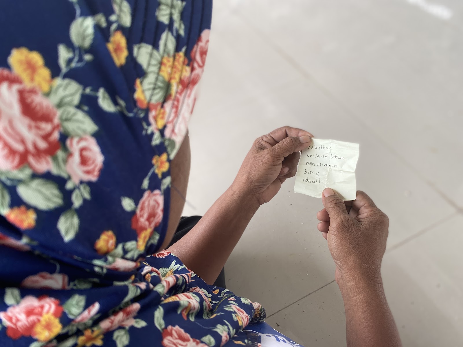 Female PPDL Farmer in Hijab revealing papers containing quiz in text