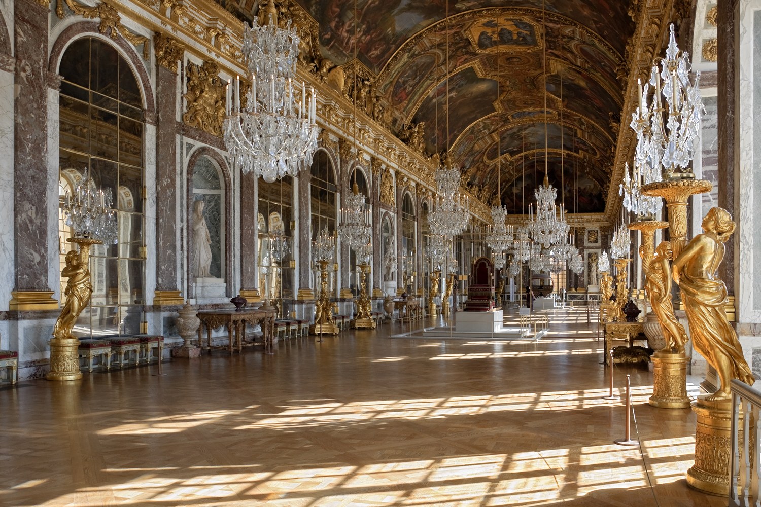 Hall of Mirrors at the Palace of Versailles showing mirrored arches, crystal chandeliers and parquet flooring