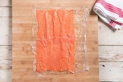 Cá hồi cắt lát mỏng cá hồi. Trong tô lớn trộn đều 200g phô mai mềm với 40g sốt cà chua, 1/3 muỗng cà phê muối, 1/4 muỗng cà phê tiêu. Tiếp đến, trái các lát cá hồi ra mặt phẳng, phết 1 lớp mỏng đều lên cá hồi cuộn tròn lại giống như kimbap là được.