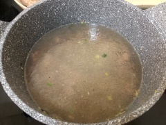 Làm nóng 1.5 muỗng canh dầu ăn trong nồi. Cho đầu hành trắng vào phi thơm. Tiếp tục, cho thịt bò vào xào sơ trên lửa lớn. Khi thịt bò đã chuyển màu sậm đều. Cho khoảng 1.5 tô nước loc vào nồi.