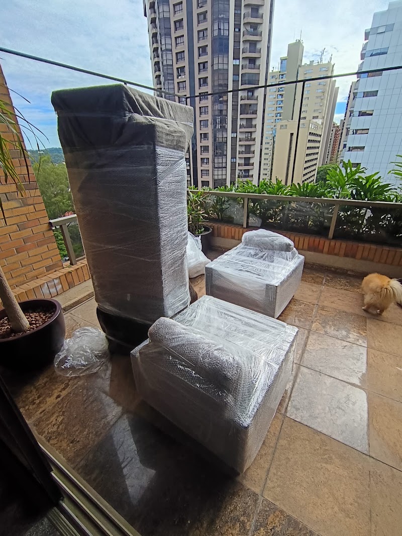 Móveis embalados pela Lev' Mudanças em varanda com prédios de São Paulo ao fundo