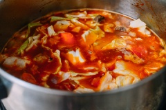 Sau đó cho cà chua vào cùng 2 muỗng tương cà, khuấy đều lên đến khi hòa tan hết nguyên liệu, để vài phút. Sau đó chế 2.5 lít nước vào, vặn lửa lớn rồi cho cà rốt, bắp cải vào nồi với 5 lá nguyệt quế, 2 muỗng muối, 1 muỗng tiêu. Khuấy đều, đậy nắp nấu đến khi sôi thì hạ nhỏ lửa đun tiếp 60 phút. Sau cùng cho khoai tây vào , nấu tiếp 30 phút nữa đến khi khoai chín mềm. Nêm nếm lại cho vừa miệng là xong rồi đó.