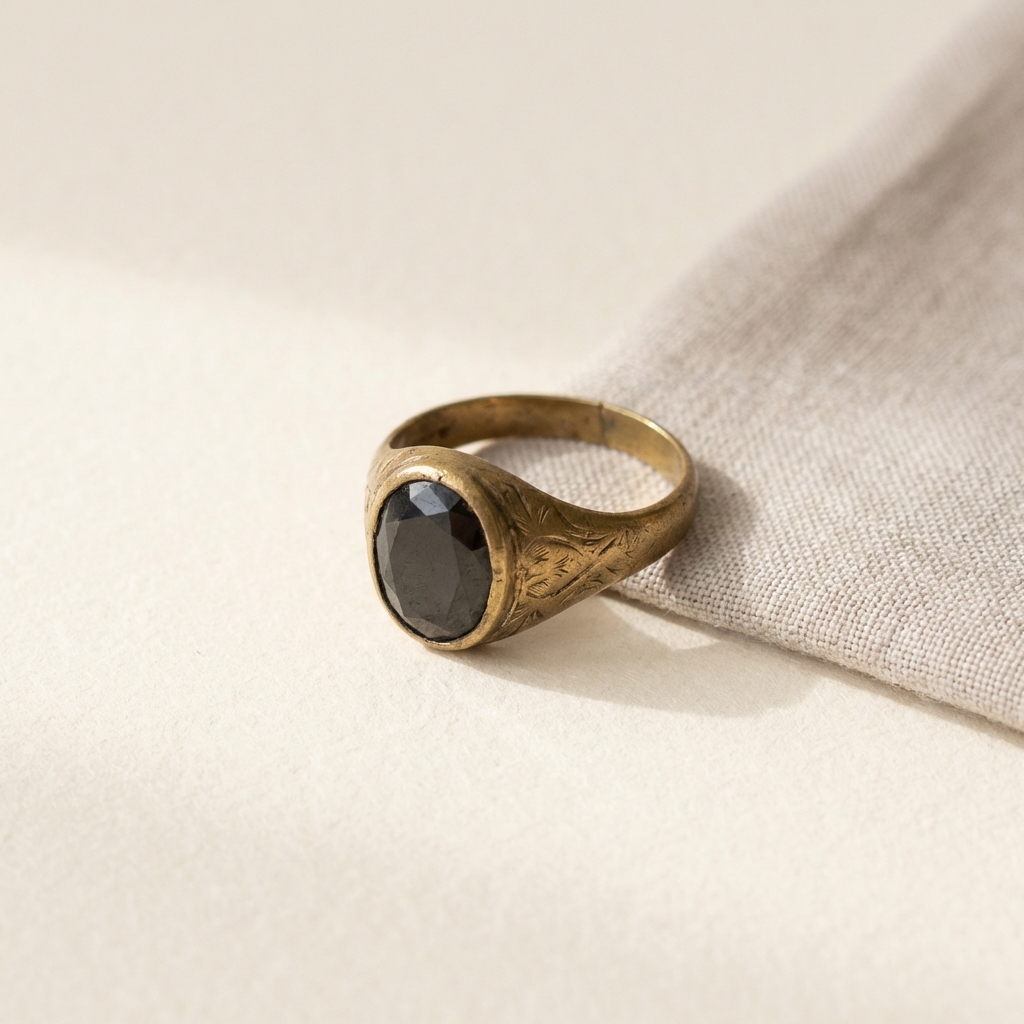 antique widows ring centered on cream background minimalist product photo with warm brass accent and soft natural light