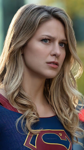 Close-up portrait of Kara Danvers in the Supergirl suit with blonde hair and a focused expression outdoors.